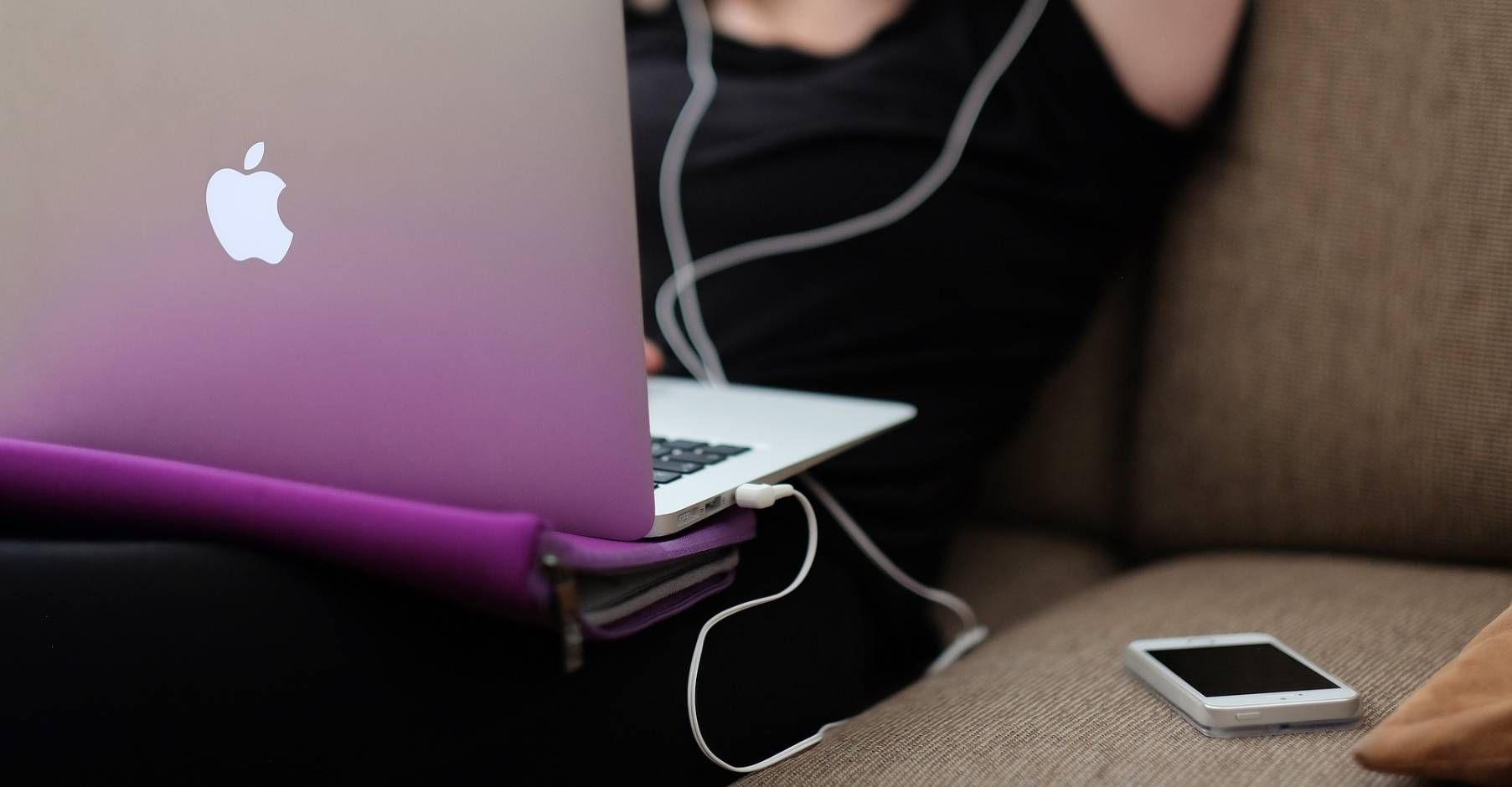 Smartfon w dłoni kobiety, biurko, na którym jest laptop, tablet i okulary przeciwsłoneczne - Co to jest Technika Pomodoro?